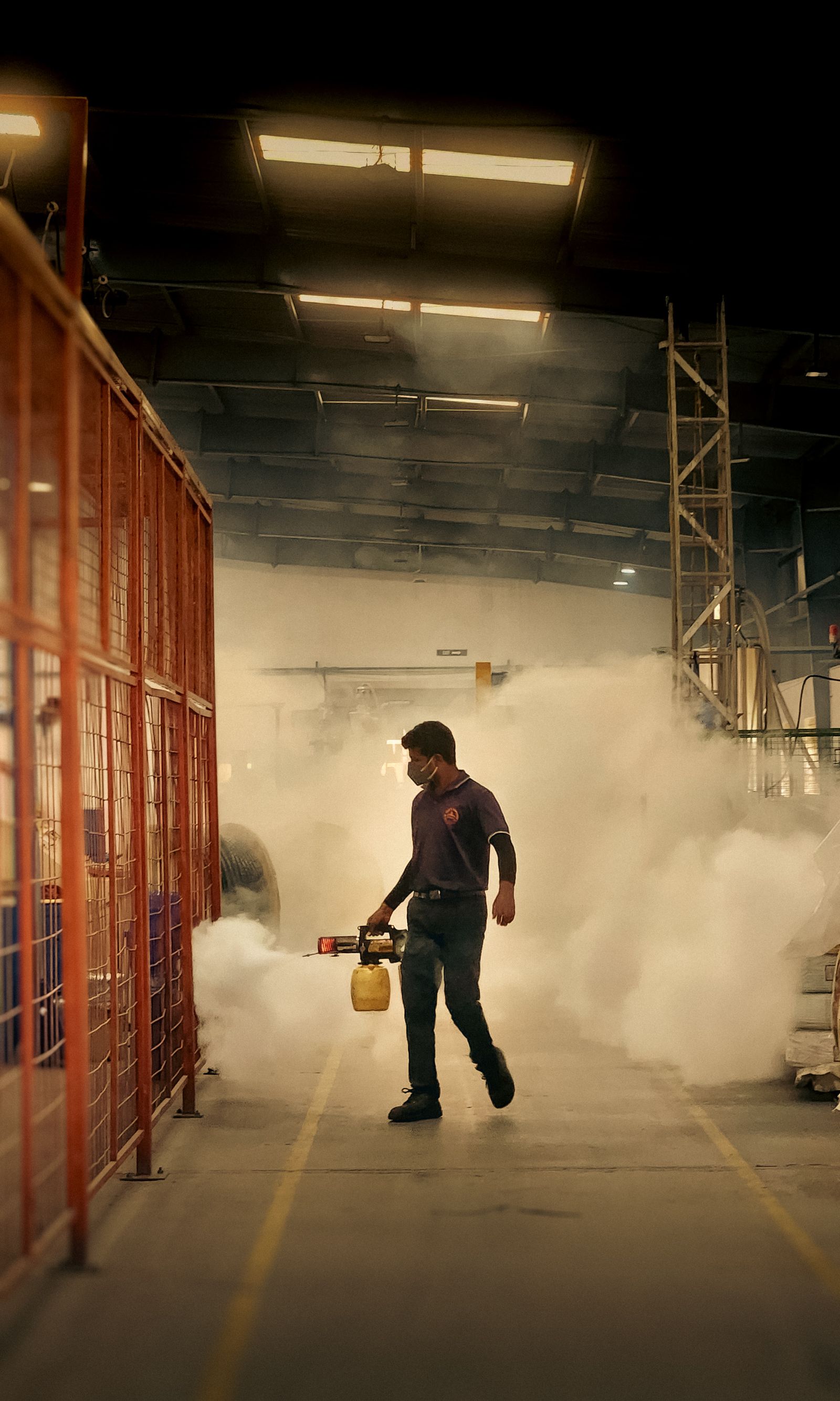 Pest-control worker carrying out fogging inside an industrial warehouse