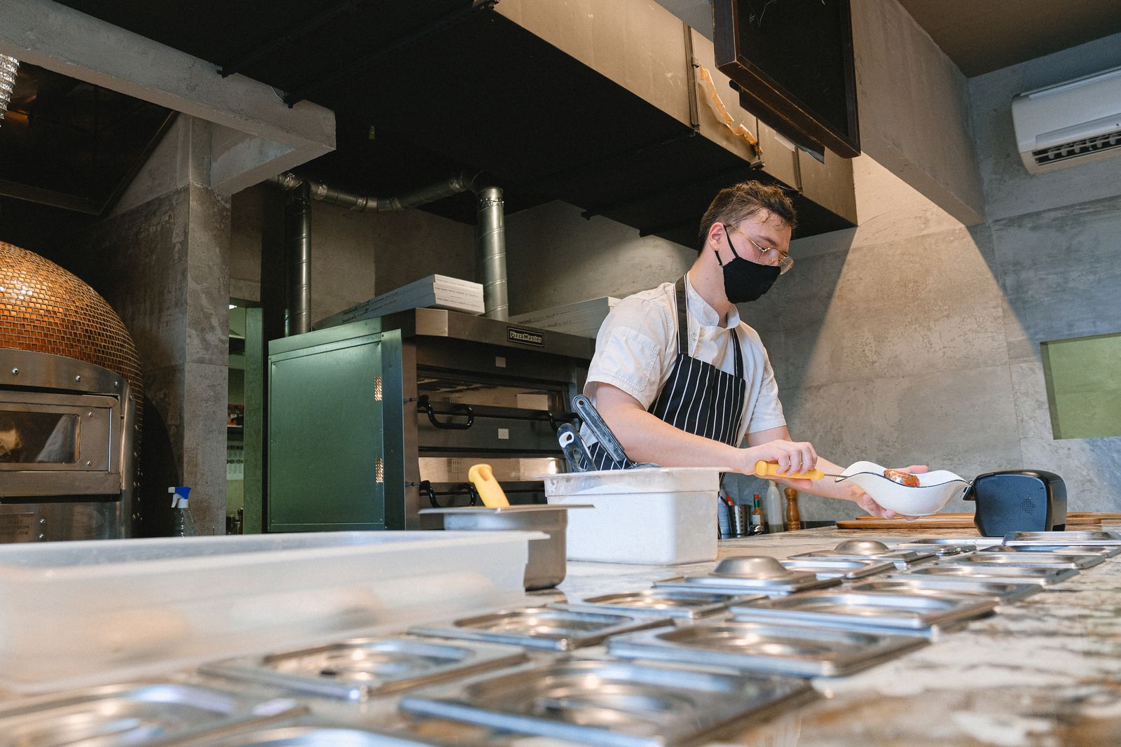 Professional working in a commercial kitchen beneath ventilation equipment